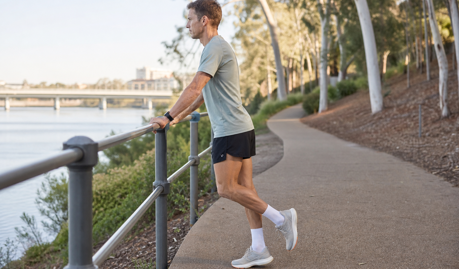 Runner performing a supported single-leg calf raise beside an Australian riverside path