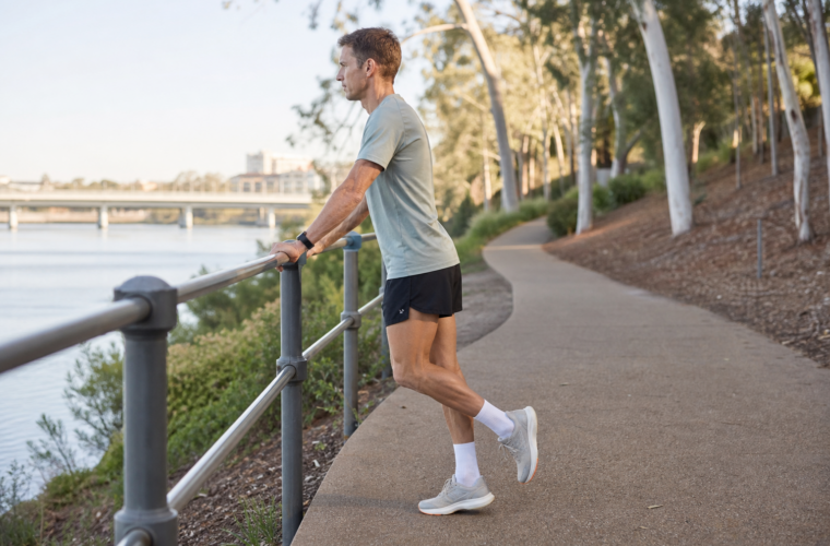 Runner performing a supported single-leg calf raise beside an Australian riverside path